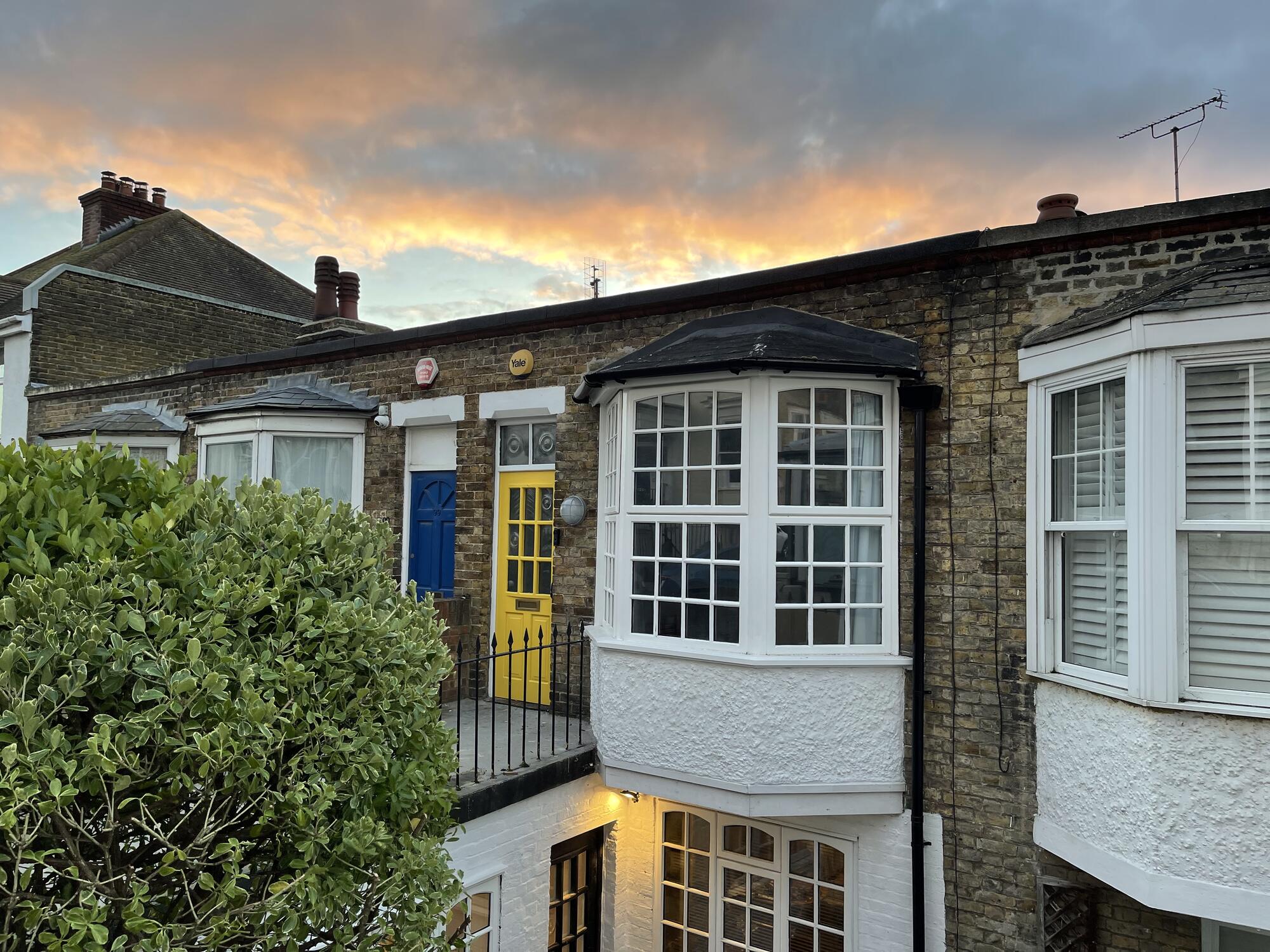 The front of the house at dusk, with its mustard yellow door